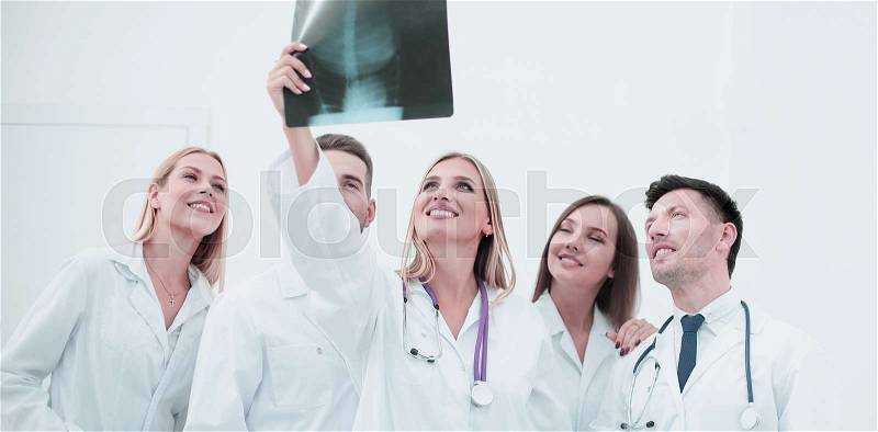 Smiling doctors working at office desk and analyzind the x-ray, medical office interior on background, stock photo