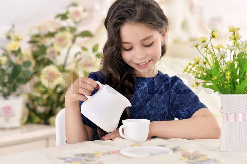 Portrait of a cute girl pouring tea, stock photo
