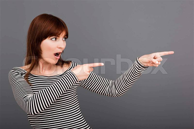 Young woman looking and pointing to her left side, stock photo