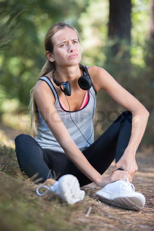 Fitness woman suffering painful ankle sprain injury, stock photo