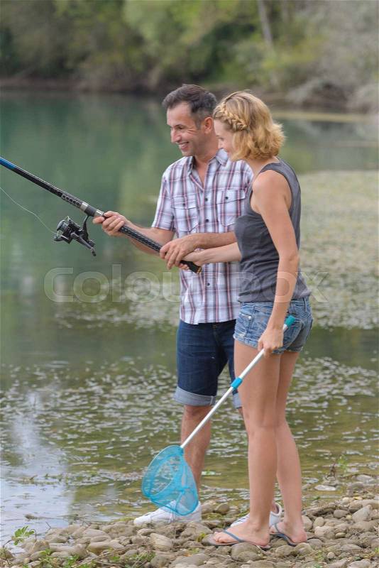 Lovely young couple fishing together by a lake, stock photo