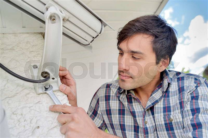Cautious man installing a security camera, stock photo