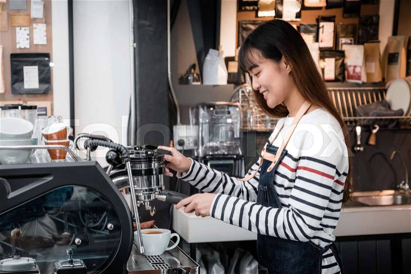 Asia female Barista wear apron making hot coffee menu for customer at counter bar,smiling Owner coffee business concept,food and drink service, stock photo