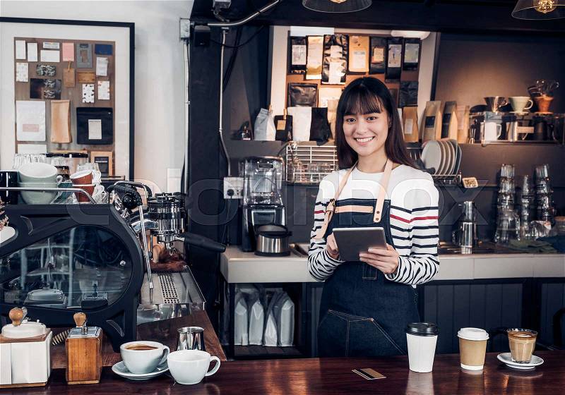 Woman barista take order with tablet,asia female waitress using digital device in coffee shop business at counter bar in cafe,moder food owner business start up, stock photo