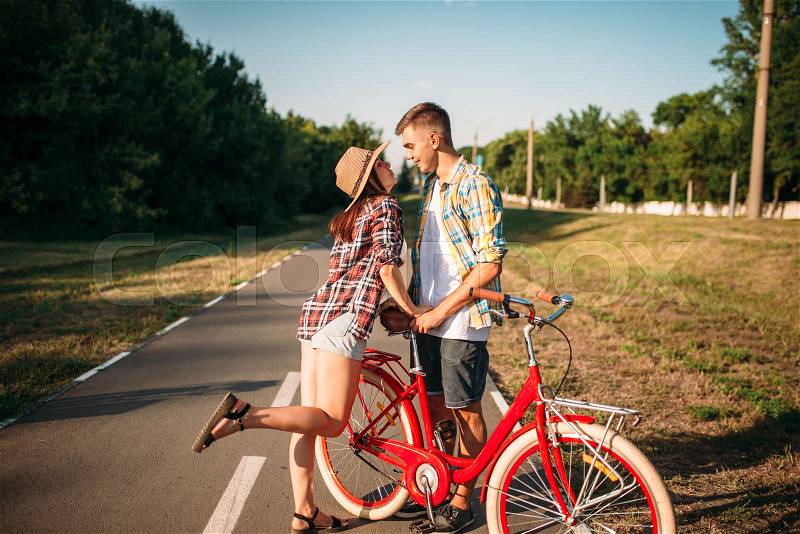 Love couple with vintage bicycle walking in summer park, romantic date of young man and woman. Boyfriend and girlfriend together outdoor, retro bike, stock photo