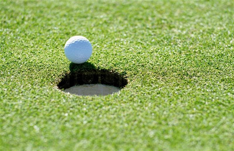A golf ball just about to go in the hole from a long putt, stock photo