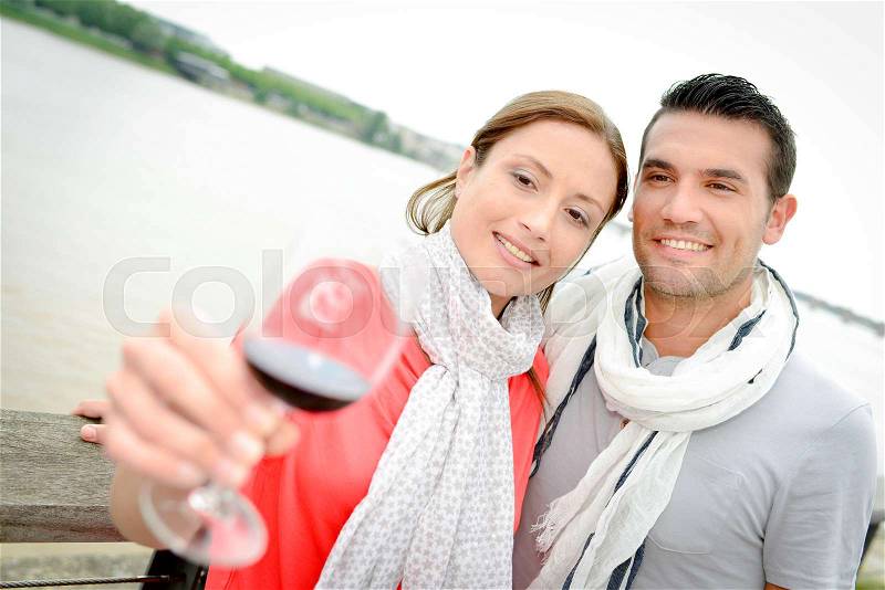 Couple drinking wine by the river, stock photo