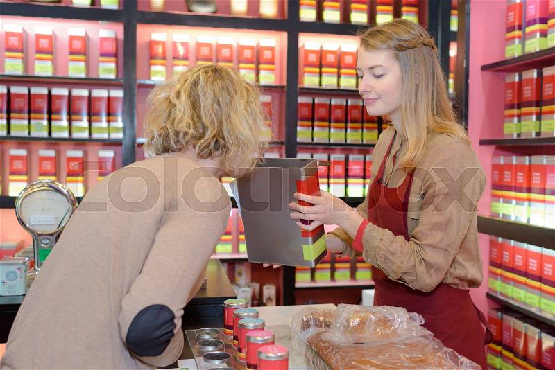 Shop assistant offering product for customer to smell, stock photo