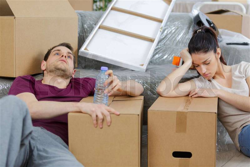 Tired couple with boxes moving into new home apartment, stock photo