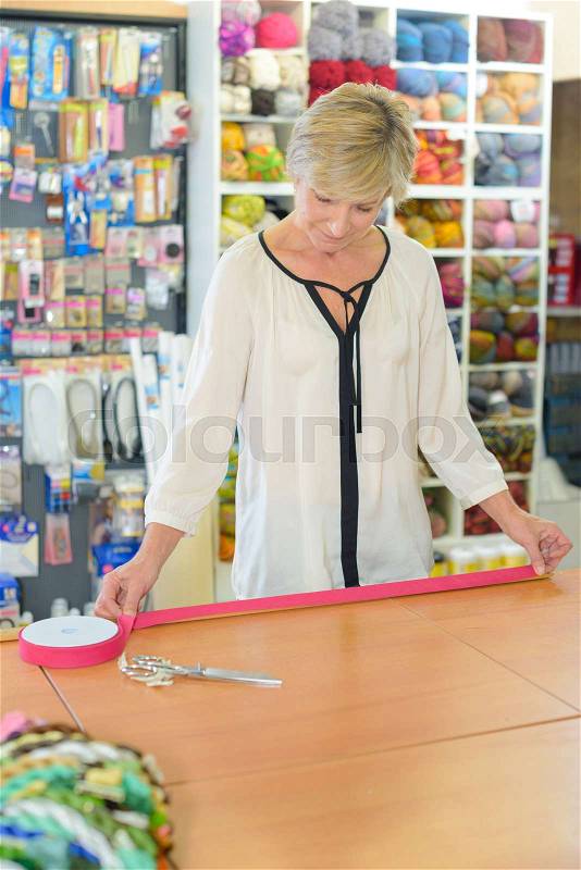 Female shopper searching for suitable fabric in drapery shop, stock photo