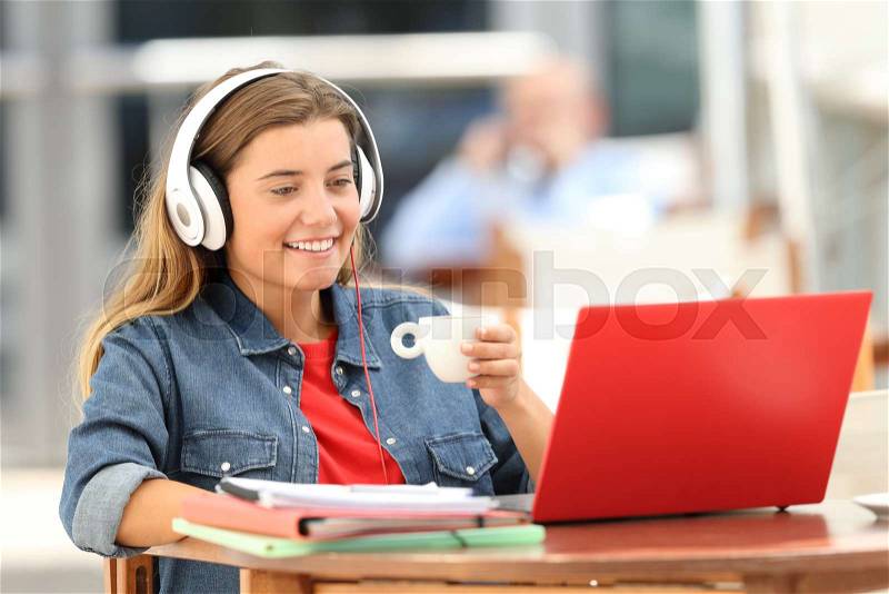 Single relaxed student female watching and listening media content on line sitting in a coffee shop, stock photo