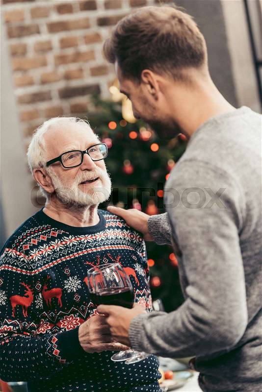 Happy senior man and his son clinking glasses on christmas, stock photo