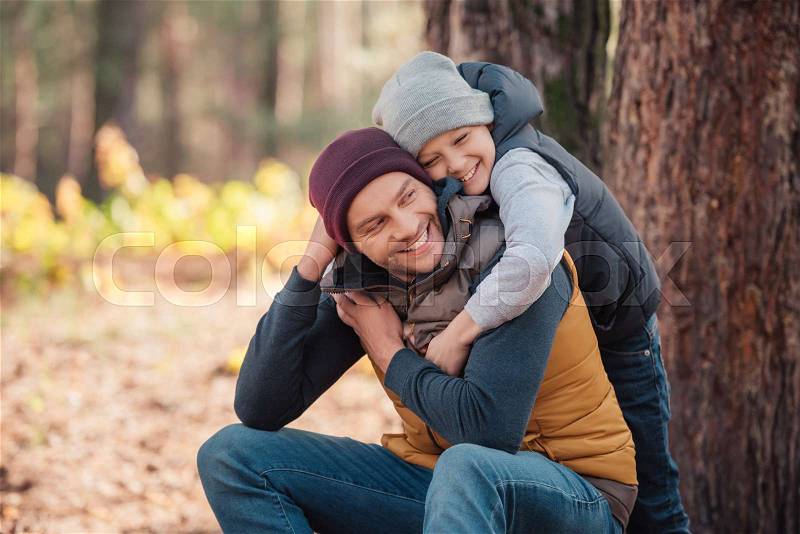 Happy father and son hugging in autumn forest, stock photo