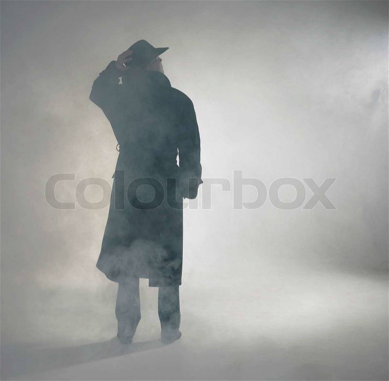 Woman wearing trench coat and standing in fog, stock photo
