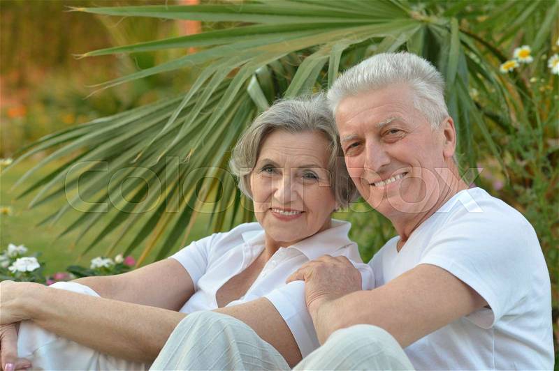 Senior couple sitting at tropic hotel garden, stock photo