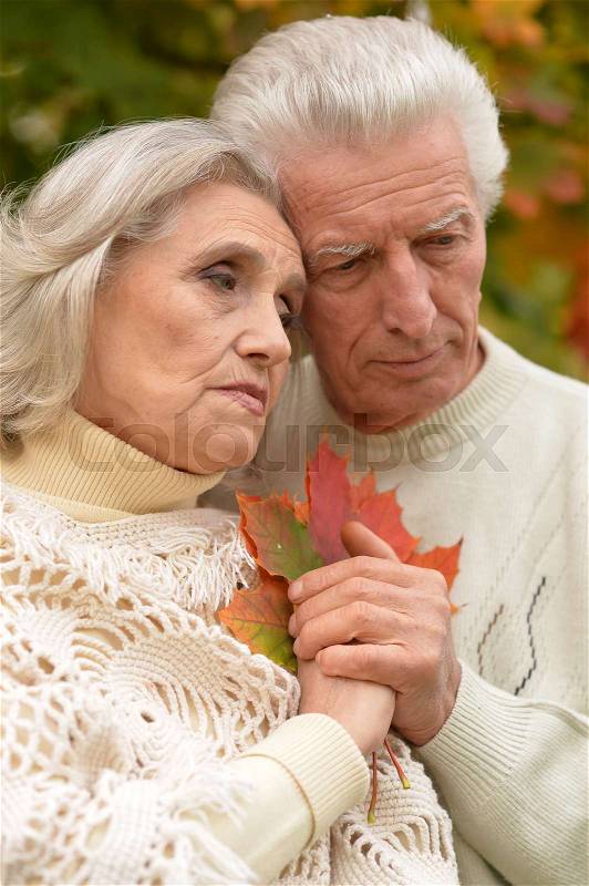Portrait of sad senior couple in autumn park, stock photo