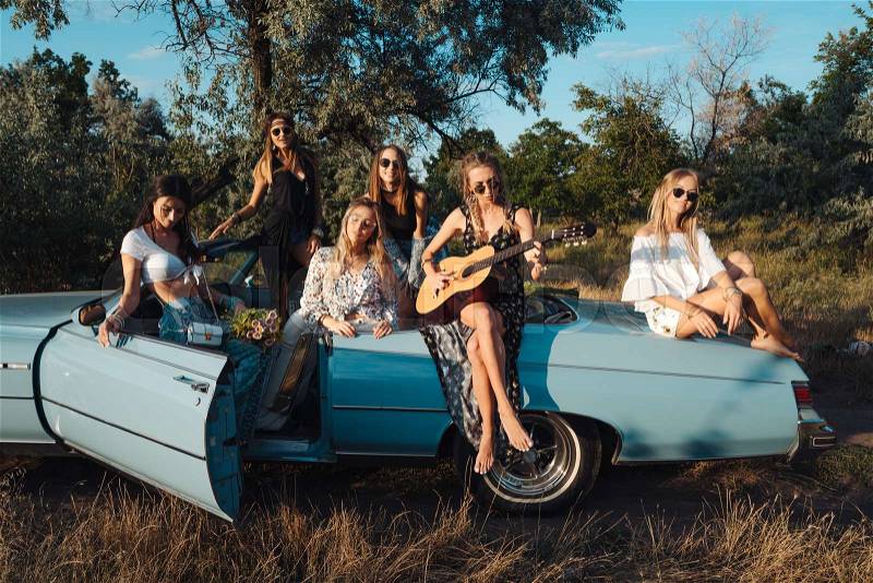 Six girls have fun on the car in the countryside, stock photo