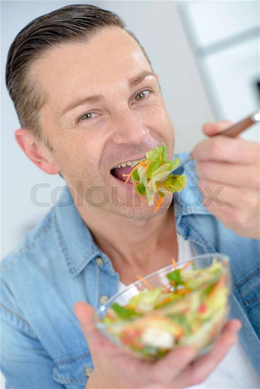 Man eating salad, stock photo