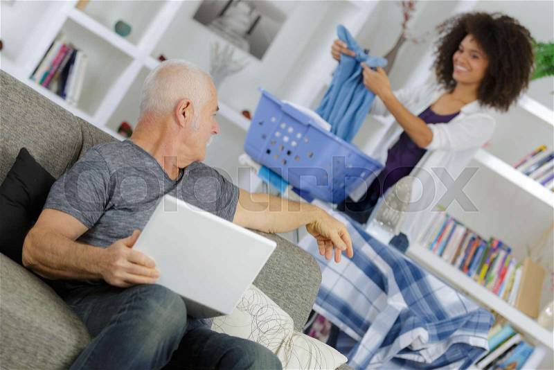 Old man using laptop while talking to care assistant, stock photo