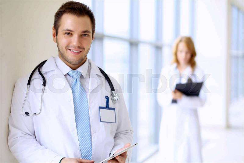 Smiling doctor man standing straight in clinic, stock photo