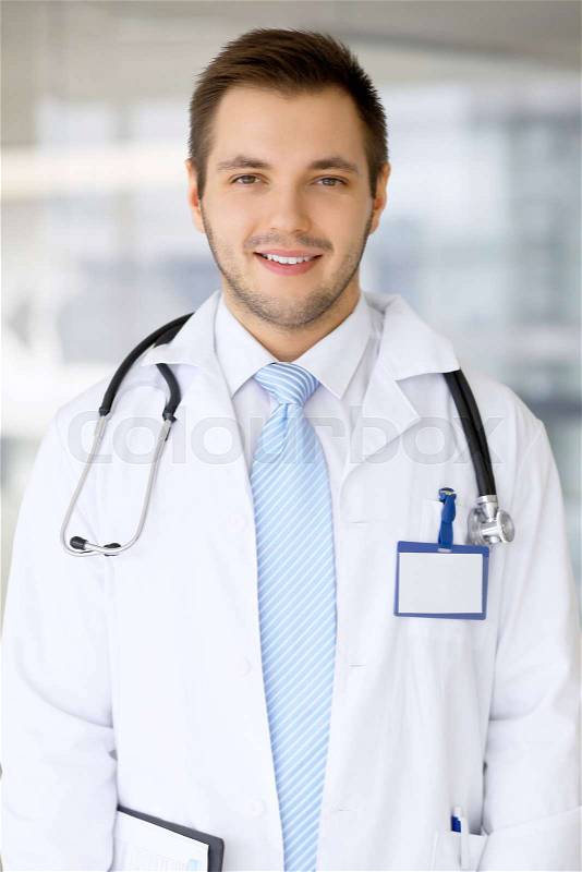Smiling doctor man standing straight in hospital, stock photo