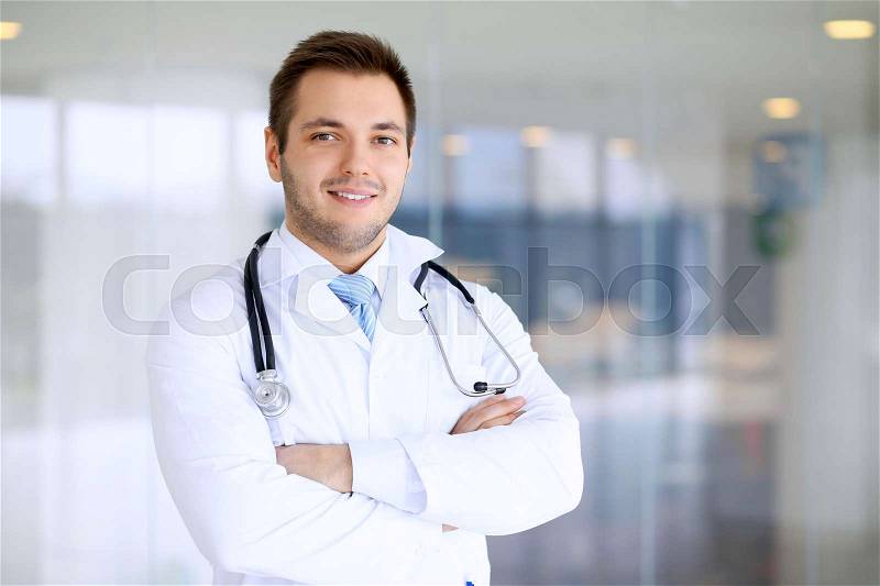 Smiling doctor man standing straight in hospital, stock photo