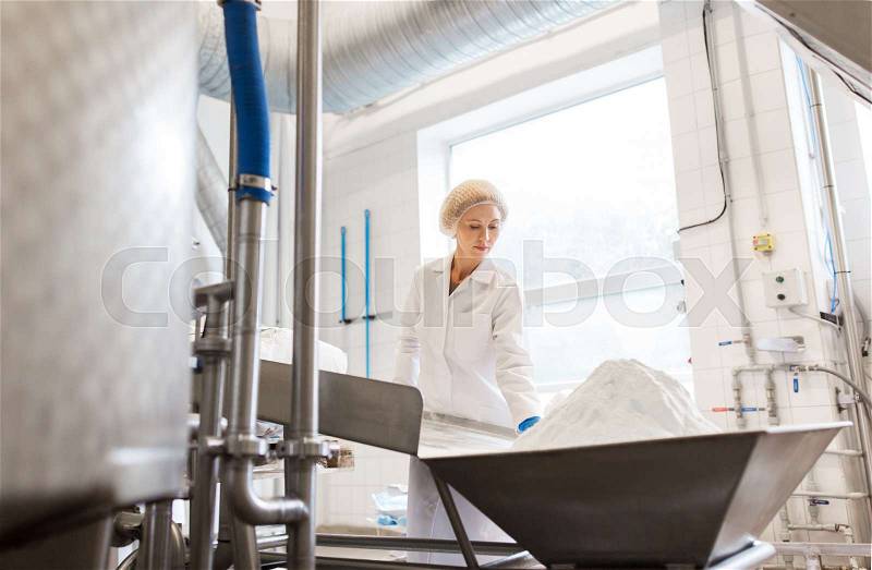 Manufacture, industry, food production and people concept - woman working at ice cream factory conveyor with powdered milk, stock photo