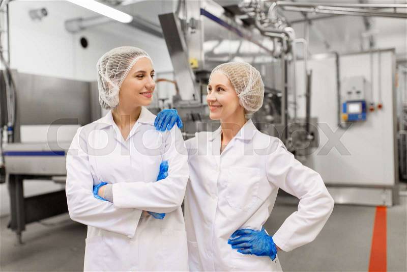Manufacture, industry and people concept - happy women technologists at ice cream factory shop, stock photo