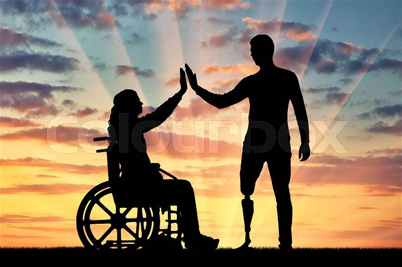 A silhouette of a woman in a wheelchair and a man with a prosthetic leg standing to support each other. The concept of people with disabilities, stock photo