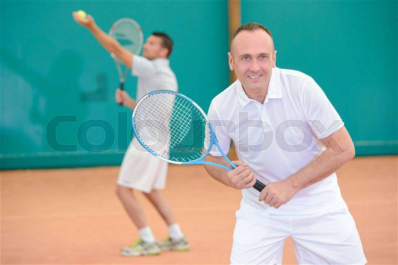 Men playng tennis doubles, stock photo