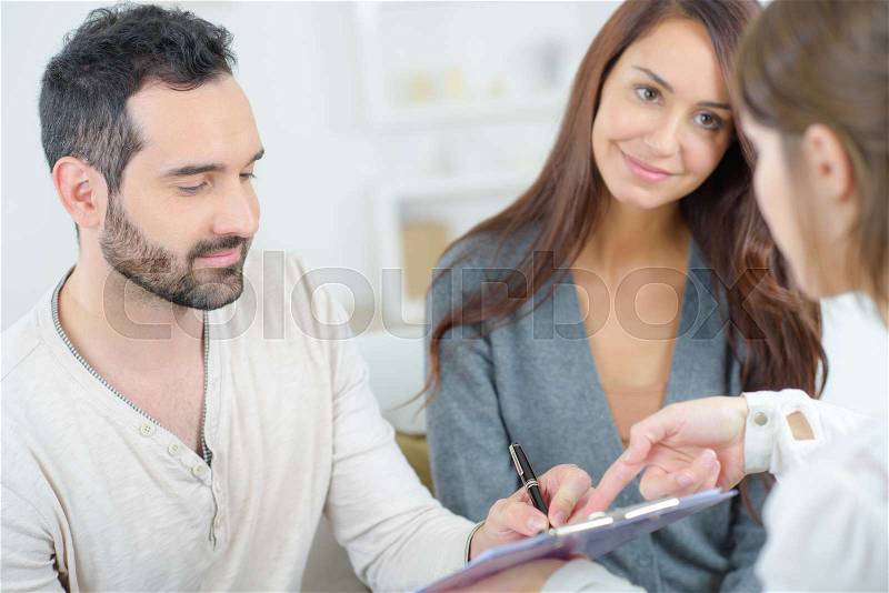 Couple at home signing paper, stock photo