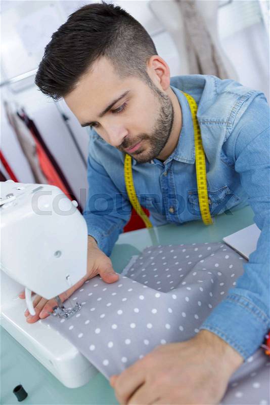 Oung man sewing a dress in his studio, stock photo