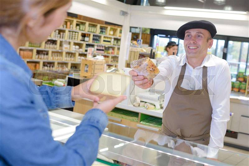 Man in French atire passing cheese to customer, stock photo