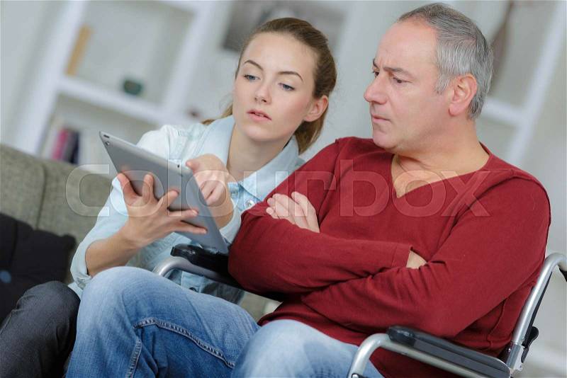 Man in wheelchair learning to use a tablet, stock photo