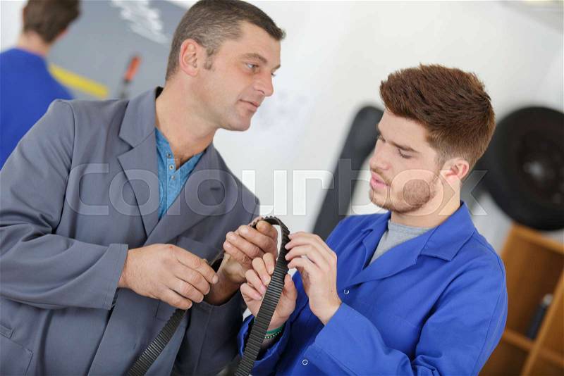 Teacher helping student training to be car mechanics, stock photo