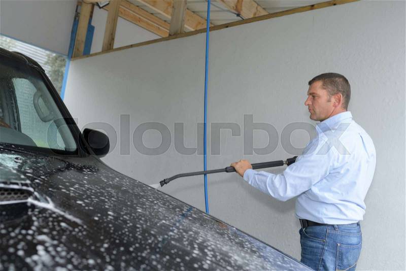Man cleaning car with high pressure washer, stock photo