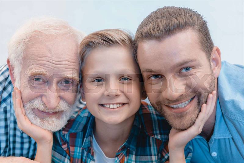Portrait shot of little boy, grandfather and father smiling and looking at camera, stock photo