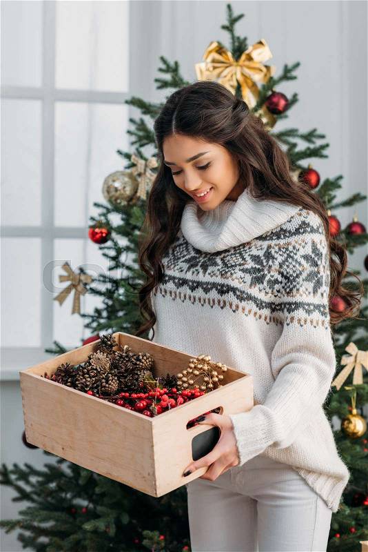 Happy beautiful woman with box of natural christmas decor, stock photo