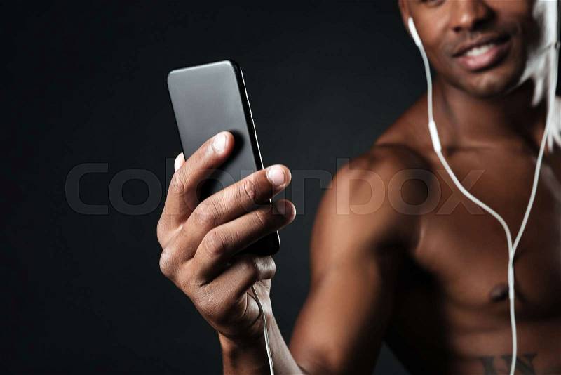 Cropped photo of handsome afro american man chatting while listen to music, over black background, stock photo