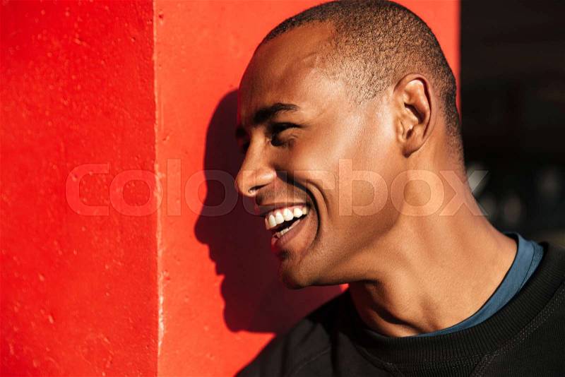 Close up portrait of a happy laughing african man looking away outdoors, stock photo