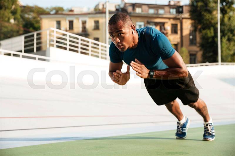Portrait of a fit afro american sportsman doing push-ups on a track field, stock photo