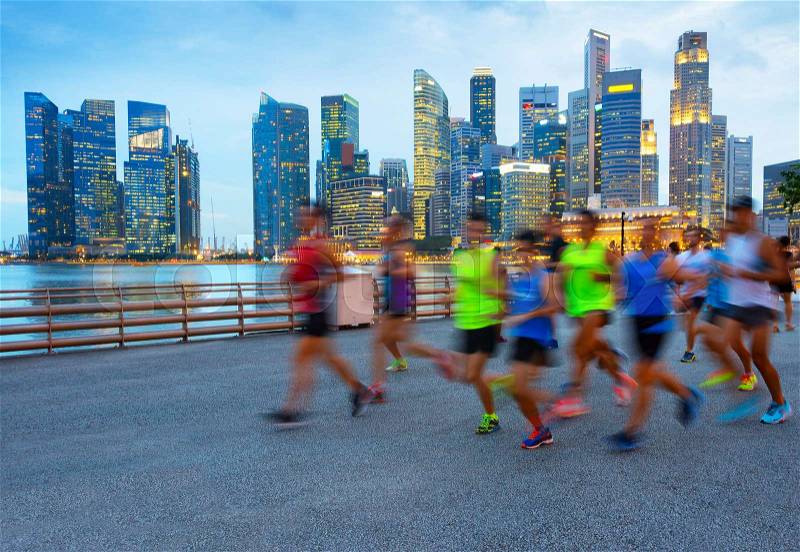 Group of runners on Singapore quayside at twilight, Singapore Downtown on a background, stock photo