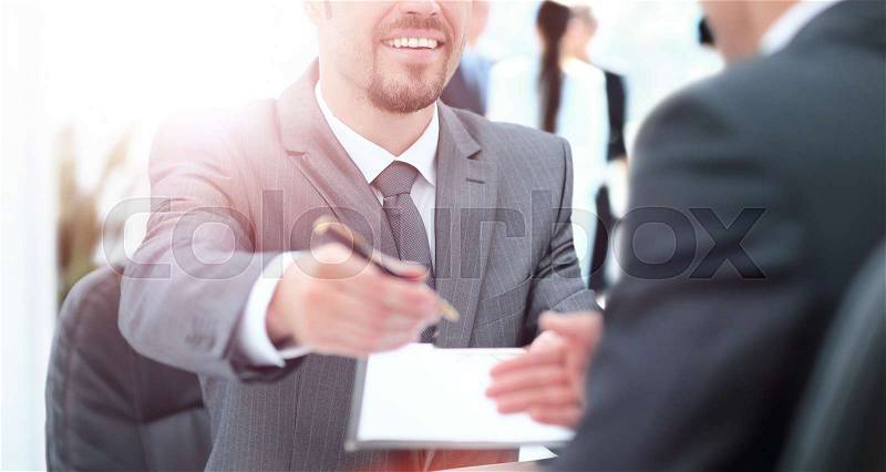 Businessman giving a pen to seal deal with his partner, stock photo