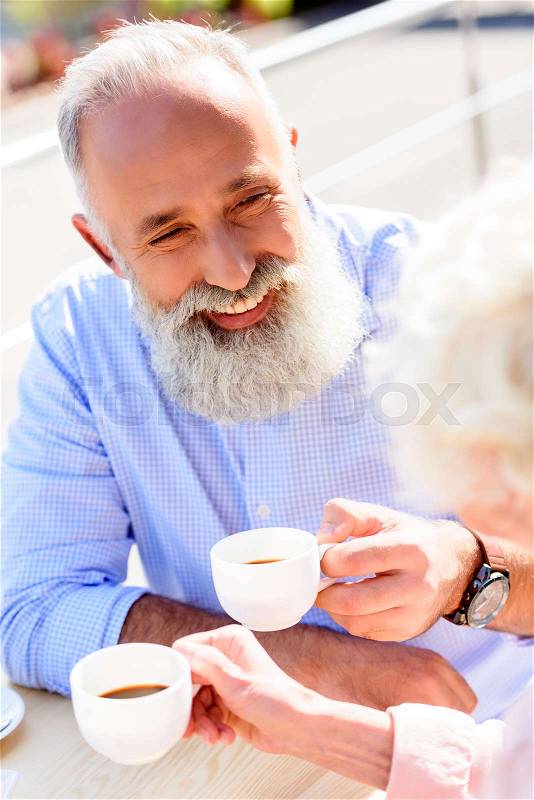 Partial view of happy senior couple drinking coffee together, stock photo
