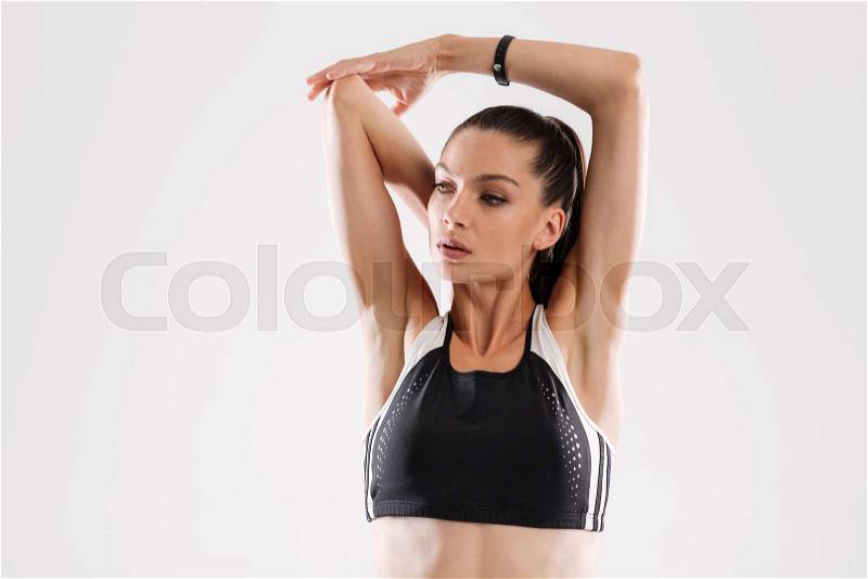 Close up portrait of a young fitness woman in sportswear stretching her hands isolated over white background, stock photo