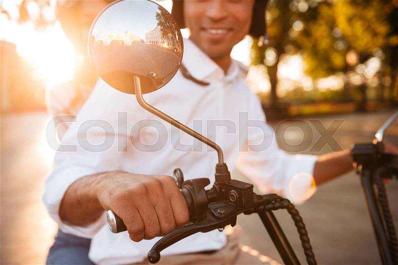 Cropped image of happy african couple rides on modern motorbike in park, stock photo