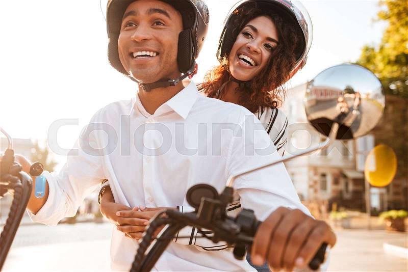 Image of Happy african couple rides on modern motorbike on the street, stock photo
