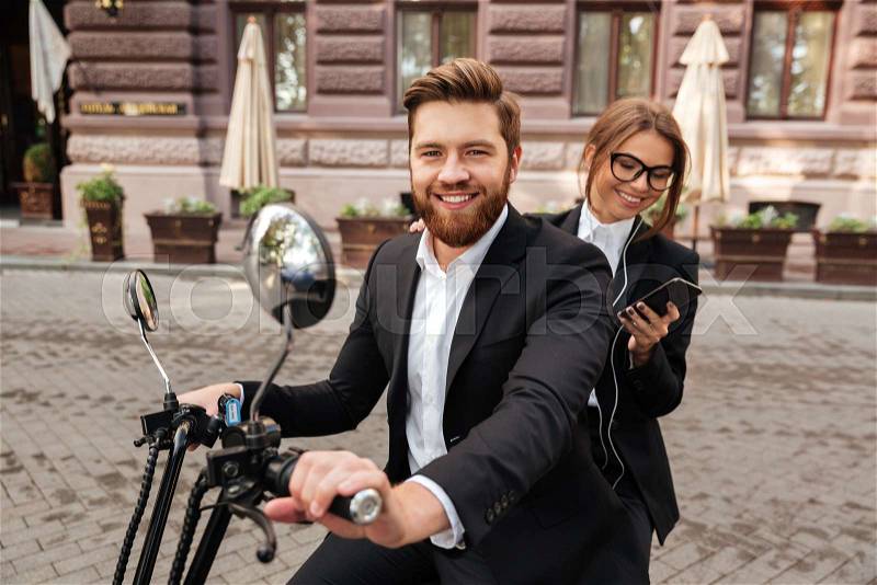 Happy stylish couple rides on modern motorbike outdoors, stock photo
