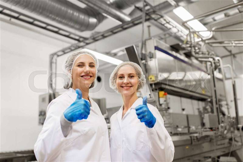 Manufacture, industry, gesture and people concept - happy women technologists at ice cream factory shop, stock photo