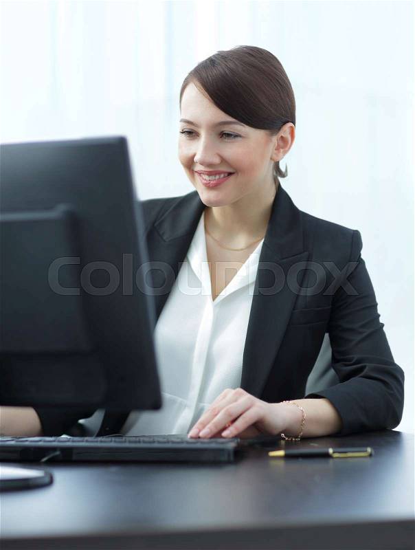 Happy businesswoman typing on computer at her desk, stock photo